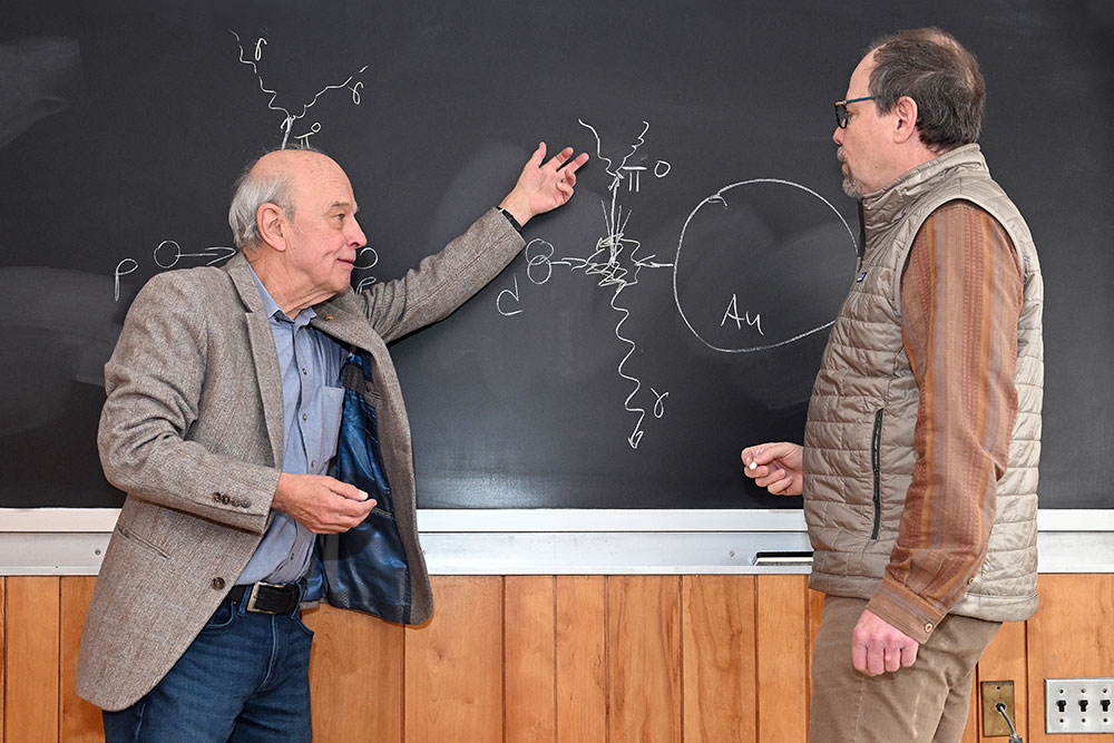 two men standing and discussing something written on a blackboard