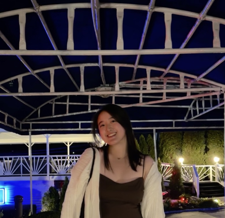 Person smiling under an illuminated archway at night.