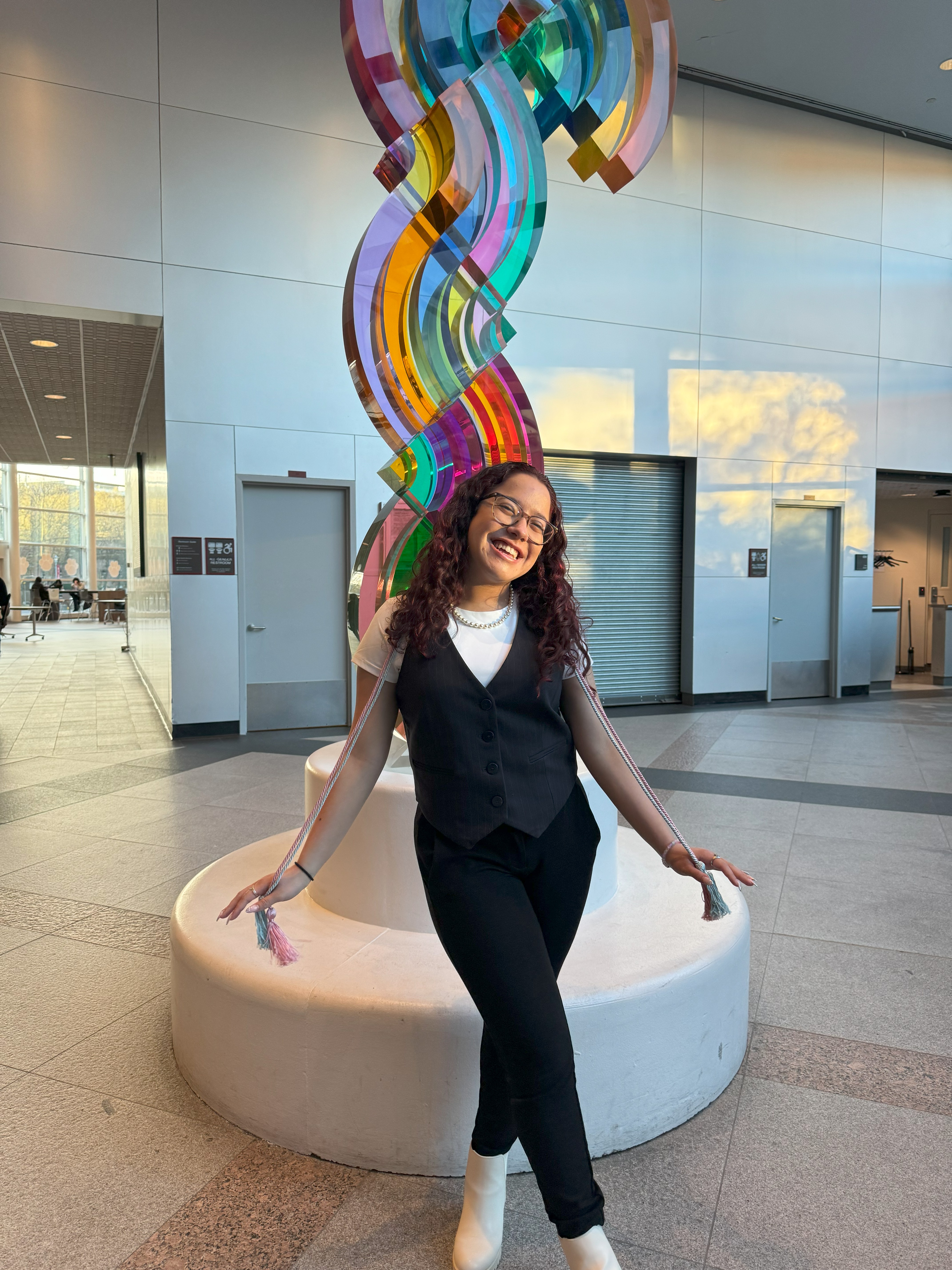 a smiling woman stands in front of a color art installation