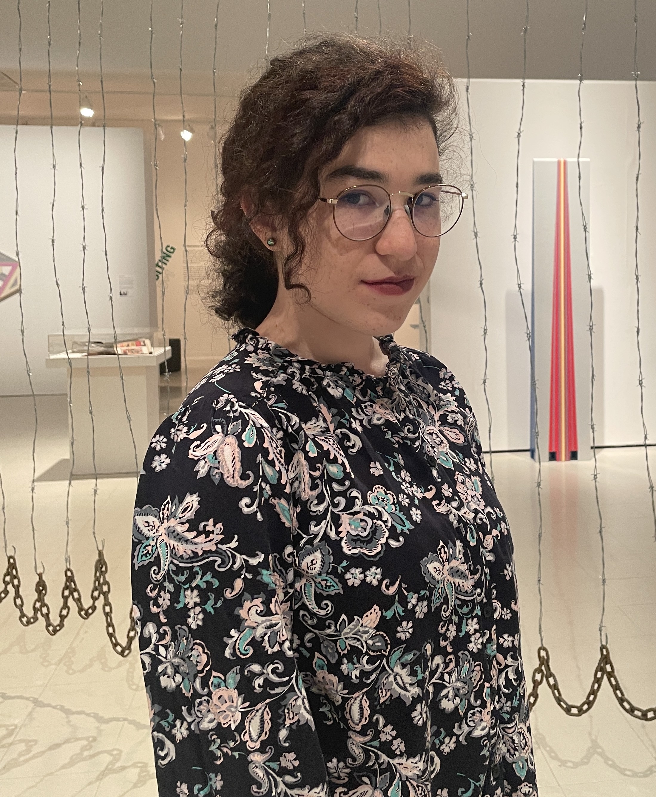 a smiling woman stands in an art gallery