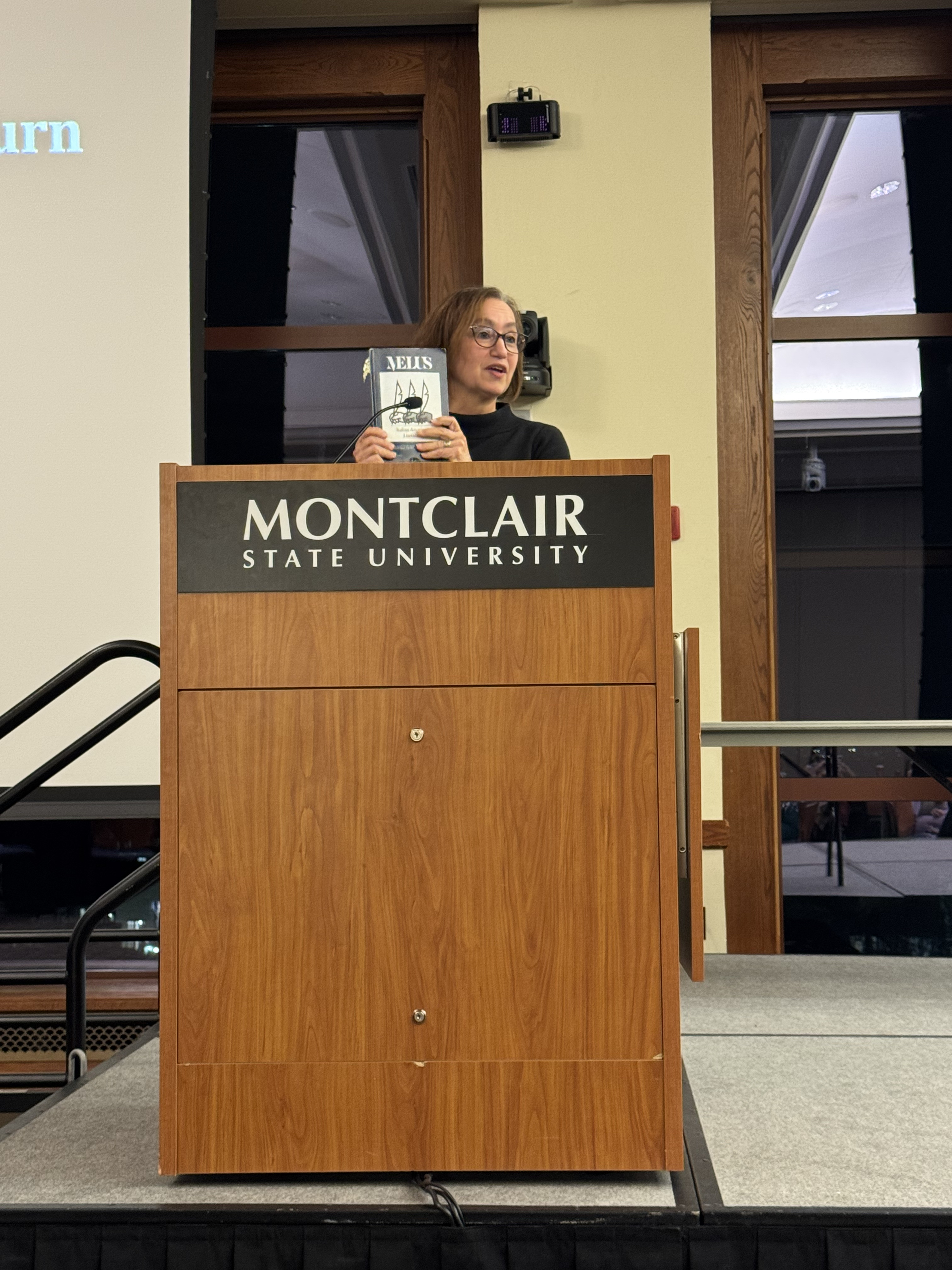 photo of Loredana Polezzi on stage, by a podium, presenting a book