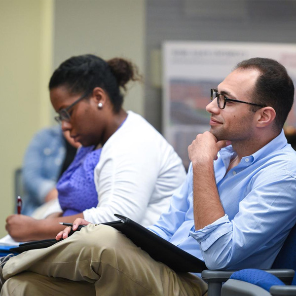 Two adults sitting in a row looking at a stage
