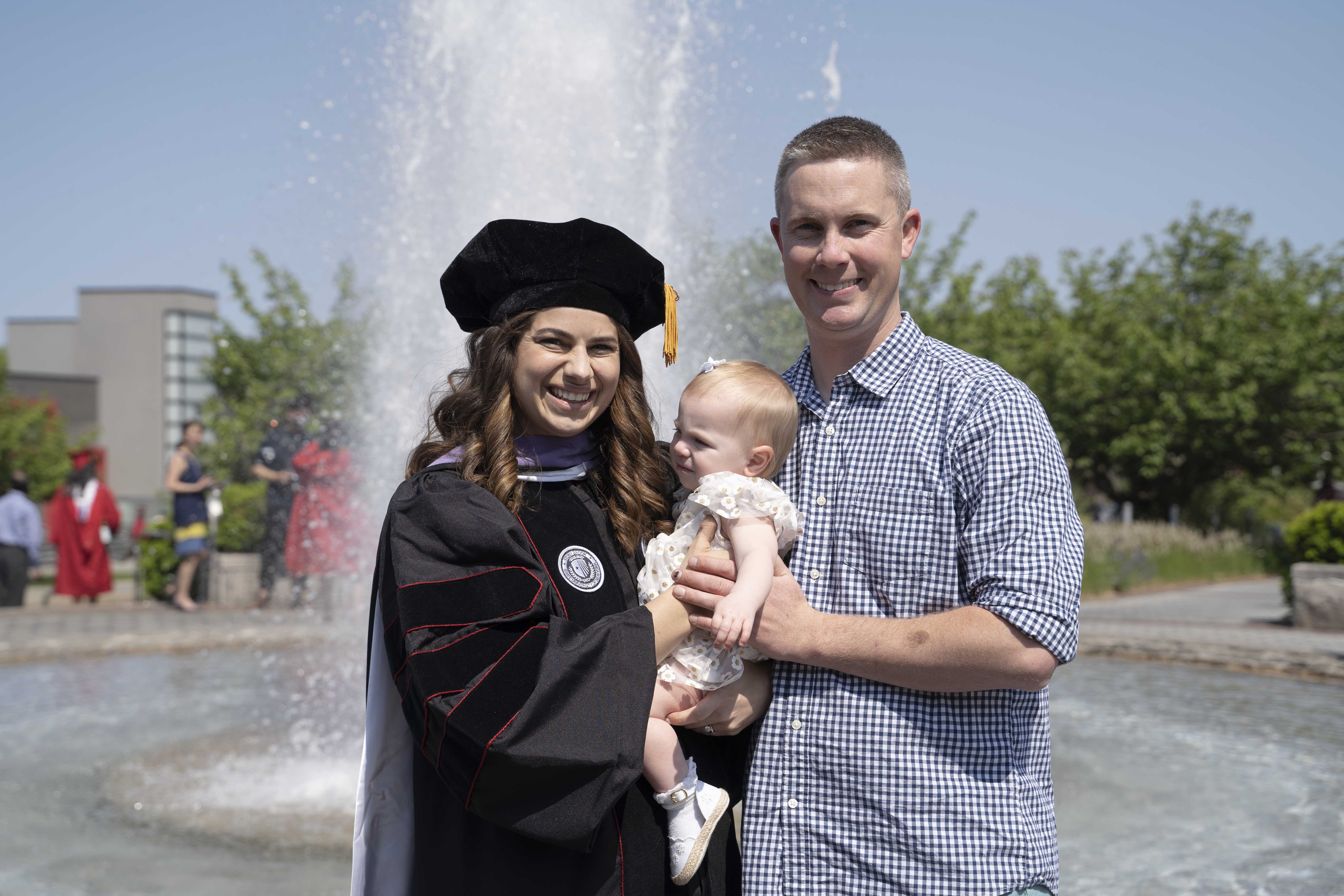 Graduate student posing with husband and baby